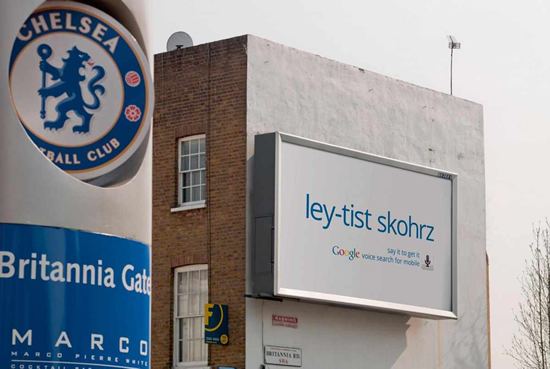 グーグル音声検索アプリケーションの屋外広告。「サッカースタジアムに入る前に、最新スコアを検索しよう」のようです。＜英国＞